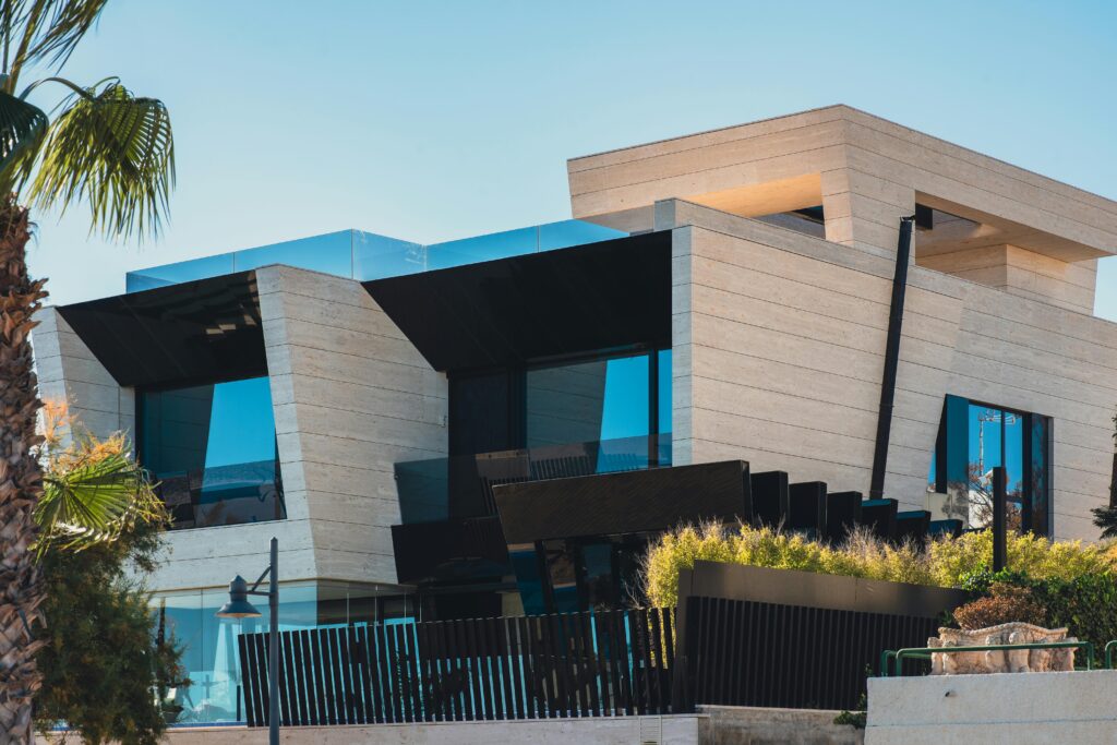 Contemporary architecture with sleek design featuring palm trees and blue sky.